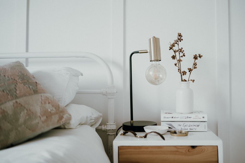 Minimal bedside table with warm reading lamp in a calm coastal bedroom