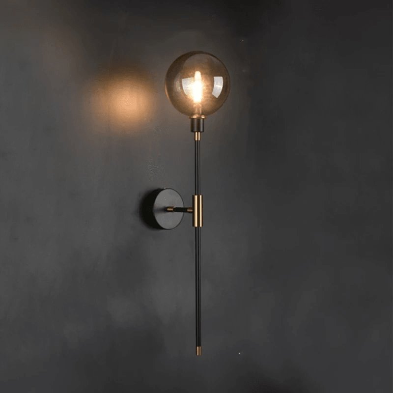 Glass wall sconce glowing softly on a white wall in a bright coastal room